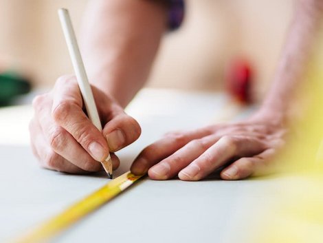 Laminat selbst verlegen, Handwerker misst Raum mit Metermaß aus, Foto: iStock / TommL