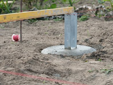 Carport bauen, mehrere einbetonierte H-Träger werden mit einer Wasserwaage ausgerichtet, bevor der Beton aushärtet. Foto: giopixel / stock.adobe.com