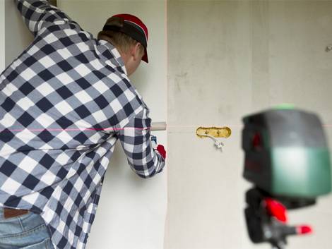 Tapezieren, Mann richtet Tapete mithilfe eines Lasers aus, Foto: artursfoto / iStock