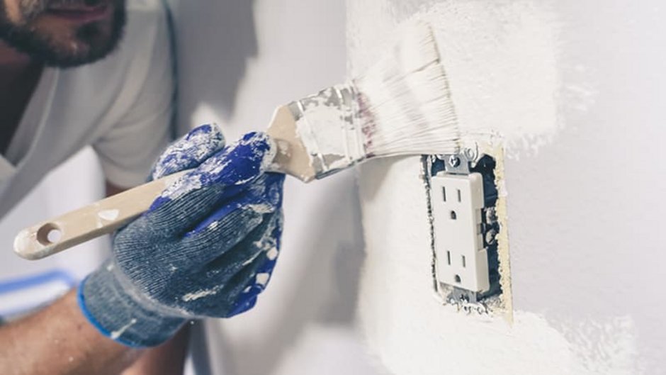 Silikatfarbe, Maler streicht Wand rund um Steckdose mit Pinsel in Nahaufnahme, Foto: iStock.com / RightFramePhotoVideo