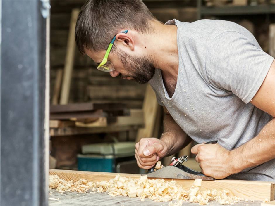 Werkstatt einrichten, Mann hobelt Stück Holz, Foto: Виталий Сова / fotolia.de