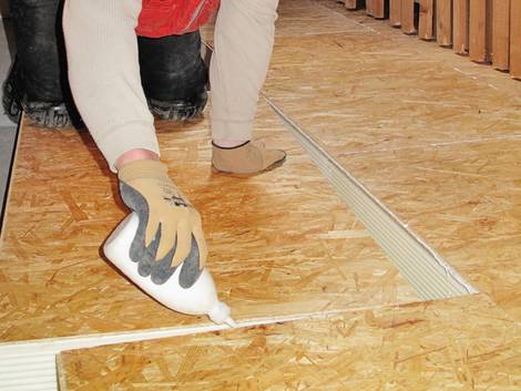 Fußbodendämmung, jemand verlegt OSB-Platten auf Dämmplatten, Foto: IVPU e.V.