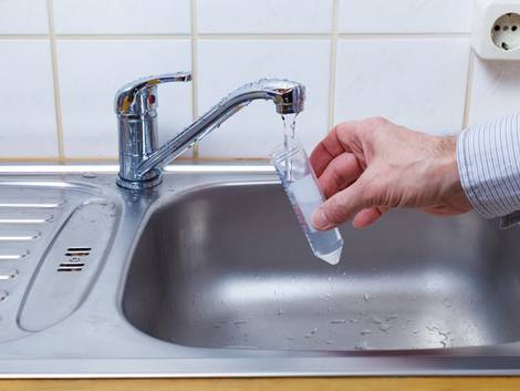 Schwimmteich, eine Wasserprobe wird aus dem Wasserhahn entnommen.