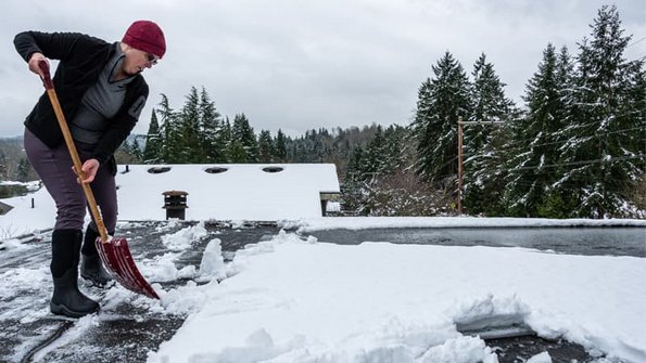 Flachdachhaus, eine Frau schippt auf einem Flachdach Schnee, Foto: knelson20 / stock.adobe.com