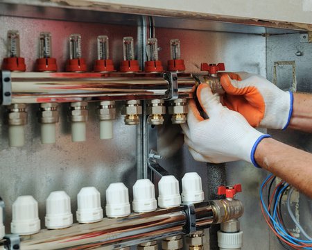 Heiztechnik, Bild von einem Installateur, der eine Fußbodenheizung einbaut, Foto: iStock.com / yunava1