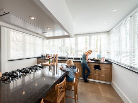 Mehrgenerationenhaus, Frau an der Spüle, ein Kind sitzt auf einem Barhocker an der Küchentheke, Foto: iStock.com / pidjoe