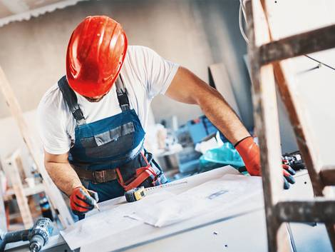 Leichtbauwand, Trockenbauwand, Bauarbeiter beugt sich über einen Bauplan, Foto: gilaxia / iStock