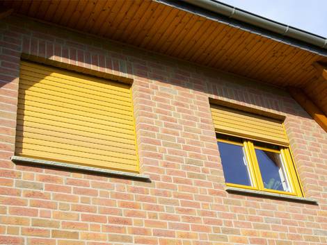 Rollladenkasten dämmen, gelber Rollladen an Backsteinhauswand, Foto: fotolia.de / Luckyboost
