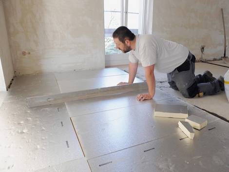 Fußbodendämmung, Handwerker verlegt Fußbodendämmplatten, Foto: IVPU e.V.