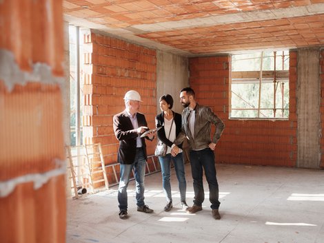 Junger Paar schaut Architekt über die Schulter.