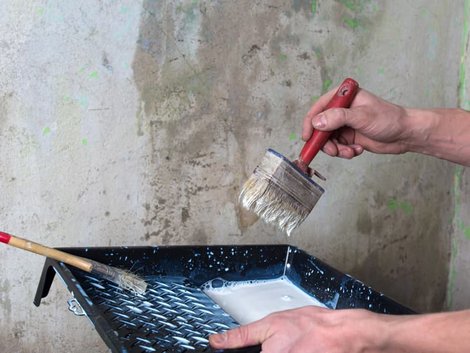 Wand verputzen, Heimwerker trägt Grundierung mit Quast auf. Foto: Yevgeniy / stock.adobe.com