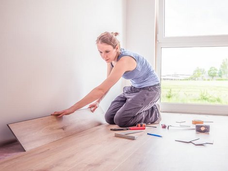 Laminat selbst verlegen, Frau verlegt letzte Reihe an der Wand, Foto: Schulzfoto / stock.adobe.com