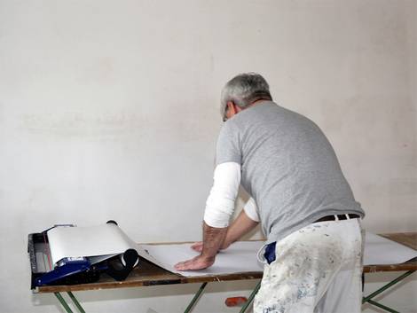 Tapezieren, Handwerker zieht Tapetenbahn durch Kleisterbad, Foto: U. J. Alexander / fotolia.de
