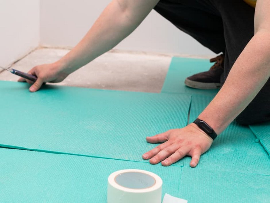 Laminat selbst verlegen, Handwerker verlegt Schutzschicht auf Estricht, Foto: iStock / Ocskaymark