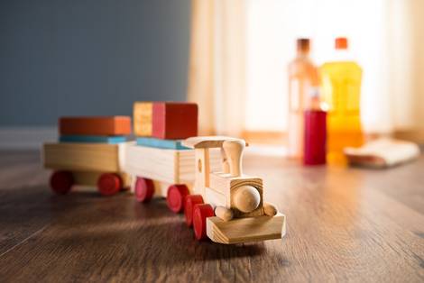 Holzeisenbahn auf Holzfußboden. Im Hintergrund Pflegeprodukte. Parkett, Schäden, Foto: stokkete/fotolia.com