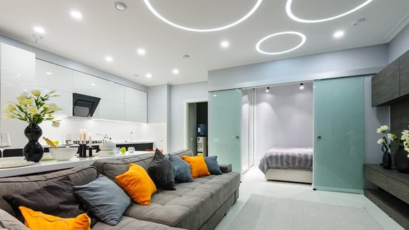 Beleuchtung, Wohnzimmer mit Spots und kreisförmiger Beleuchtung in der Decke, Blick auf das Sofa, Foto: starush / stock.adobe.de